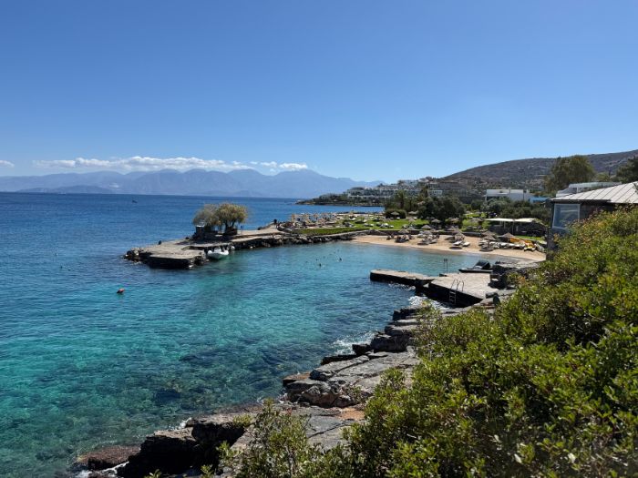 View of the turquoise Mediterranean waters and small beach at Elounda Mare hotel in Crete, Greece.